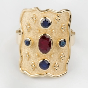 Vue détaillée d'une bague vintage en or avec rubis ovale et pierres d'accent bleues