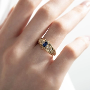 Elegante anello in oro con zaffiro taglio smeraldo e diamanti indossato sulla mano