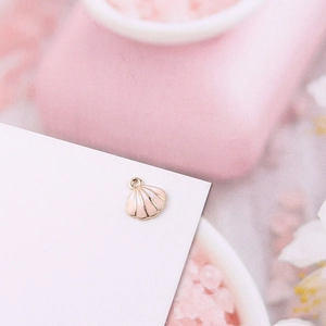 Detalle de colgante de concha esmaltada rosa con borde dorado para bisutería artesanal