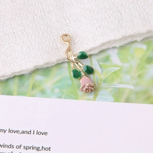 Détail macro d'un pendentif rose en alliage avec bordure dorée et feuilles vertes pour DIY