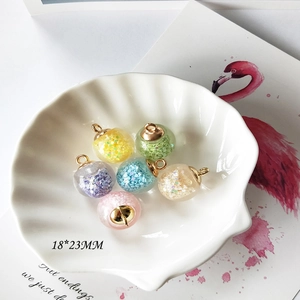 Bunte 18x23mm DIY Glasanhänger mit Glitzer in einer weißen Muschelschale serviert