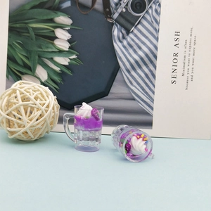 Détail de deux mini pendentifs chope de bière en résine avec jus violet et crème