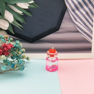 Dettaglio di un ciondolo a mini bottiglia dei desideri con paillettes rosa e stelline