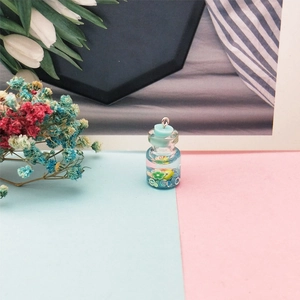 Dettaglio di un mini ciondolo a bottiglia con liquido blu e decorazioni floreali