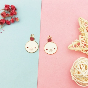Detail of two cartoon chicken alloy pendants for DIY jewelry making on a pastel background