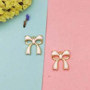Détail de breloques nœuds en émail rose et plaqué or pour la création de bijoux DIY et boucles