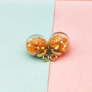 Detail of transparent glass ball charms with orange star sequins and gold metal caps