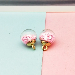 Macro view of transparent glass ball charms with pink stars and golden metal hangers