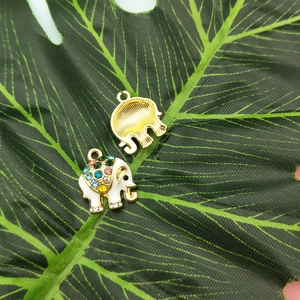 Detail of gold-plated elephant charms with colorful rhinestones on a green leaf
