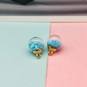 Macro shot of glass ball pendants filled with blue star sequins and gold metal loops