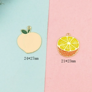 Peach and orange enamel fruit charms for DIY jewelry making in pink and blue background