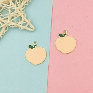 Macro shot of two peach enamel charms with gold metal edges for DIY jewelry making