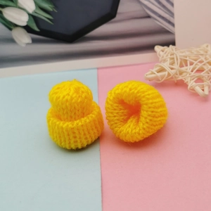 Detailed view of mini yellow knitted hats for DIY crafts and doll accessories