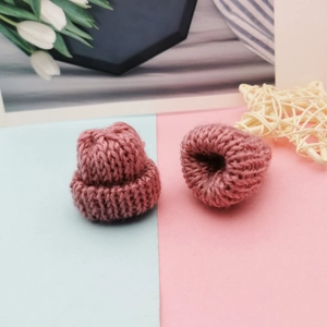 Detail shot of two pink handmade mini knitted hats for DIY doll accessories and crafts