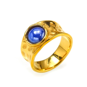 Macro view of vintage gold ring with blue gemstone and irregular hammered texture