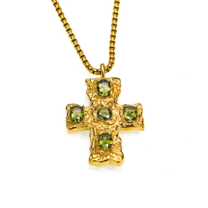 Gros plan du pendentif croix dorée avec zircons vert olive et texture en métal martelé