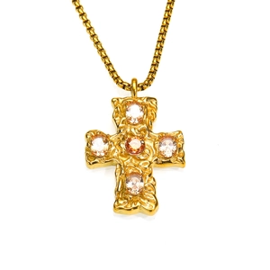 Vue macro du pendentif croix dorée avec zircones étincelantes et texture martelée