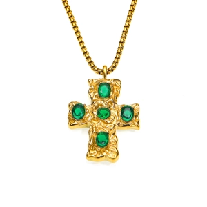 Détail du pendentif croix martelé en or avec cinq zircons verts sur chaîne vénitienne