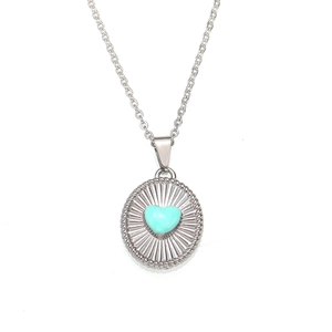 Detail of 18K gold necklace with heart turquoise stone and sunburst metal texture