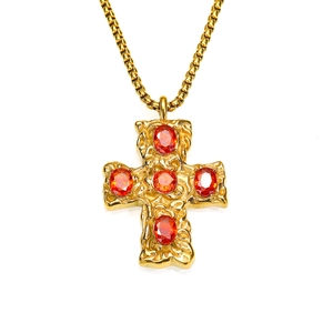 Détail du pendentif croix martelée dorée avec cinq zircons rouges sur une chaîne boîte