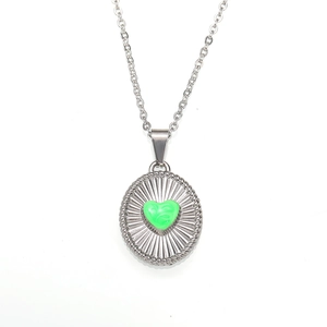 Macro detail of silver round pendant with green fluid heart and sunburst texture