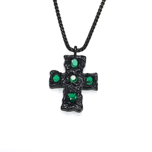 Détail du pendentif croix gothique noire avec texture martelée et pierres vertes