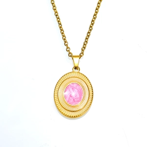 Detailed close-up of a vintage gold oval pendant with pink enamel and radial textures