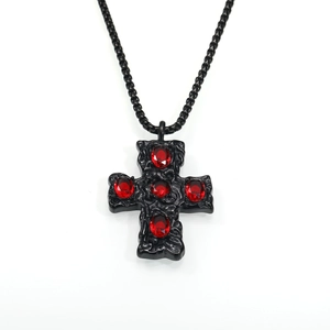 Vue détaillée du pendentif croix gothique texturé noir avec des pierres rouges
