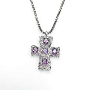 Détail d'un pendentif croix martelé avec zircons violets sur une chaîne à maillons ronds