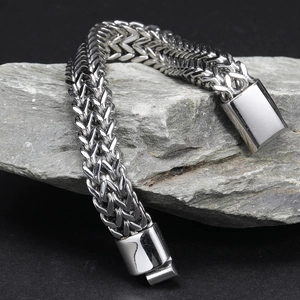 Close-up of silver stainless steel Franco chain bracelet with fold-over clasp on a stone