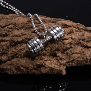 Detailed close-up of a silver dumbbell pendant with a ball chain on a rustic wood background