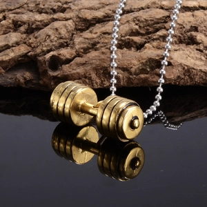 Detailed shot of a vintage gold dumbbell pendant with silver bead chain on a mirror surface