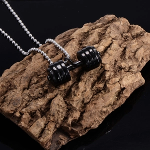Industrial black dumbbell pendant with silver bead chain on a rustic wooden surface