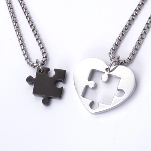 Detail of puzzle heart couple pendants in black and silver finishes on box chains
