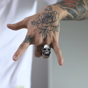 Close-up of a vintage silver skull ring with gothic details on a male hand