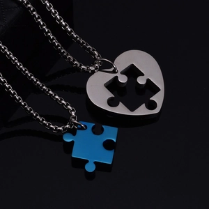 Close-up of interlocking heart and puzzle piece pendants on titanium steel box chains