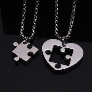 Macro shot of polished titanium steel puzzle heart pendants on black mirror background