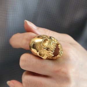Close-up of golden gothic skull ring for men worn on finger with detailed bone texture