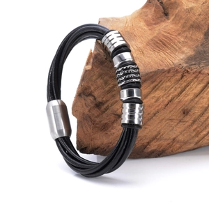 Mehrsträngiges schwarzes Lederarmband für Herren mit silbernen Ringen auf Holzdekor
