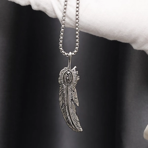 Macro del ciondolo a piuma vintage in acciaio al titanio argento con intaglio religioso