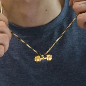 Close-up of golden dumbbell pendant necklace on a model showing box chain details