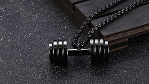 Detailed close-up of a glossy black dumbbell pendant necklace with a steel box chain