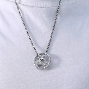 Close-up of 45 LBS barbell pendant necklace on white T-shirt showing workout jewelry details