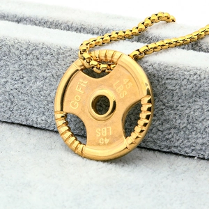 Macro shot of gold dumbbell weight plate pendant with 45 LBS and Go Fit engraving