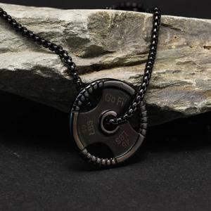 Macro shot of black plated fitness barbell plate pendant with Go Fit engraving on stone