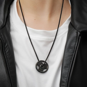 Detail of 5KG weight plate pendant with black bead chain over leather jacket