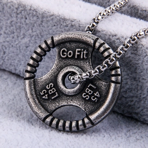 Macro shot of silver dumbbell plate pendant with Go Fit engraving on grey texture