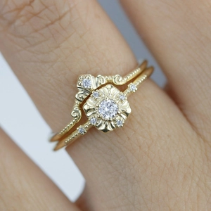Detail van vintage gouden ringen met bloemvormige diamant en verfijnde korrelrand afwerking