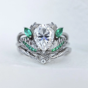 Macro detail van zilveren kroonring met peervormige steen en groene smaragden