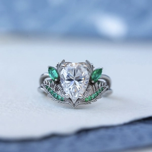 Detail macro van ring met peergeslepen witte steen en groene accenten met gegraveerde band